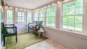 Ein Zimmer mit einer Bank, einem kleinen Tisch und einer Topfpflanze.