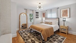 Ein Schlafzimmer mit Bett, Spiegel, Nachttisch, Teppich und Deckenleuchte.