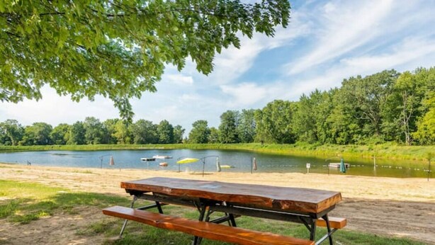 Een picknicktafel aan een meer, met boten en een steiger op de achtergrond.