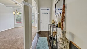 A hallway with a white door, a console table with decorative items, and a large woven vase.