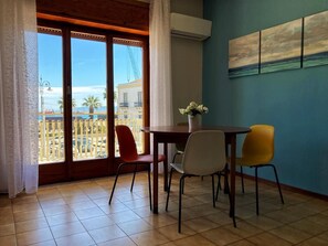 A room with a balcony, a dining table with chairs, and a painting on the wall. - Vacation home IL NIDO (Aeolian Islands boarding) WiFi/park free. CIR 19083049C21 (Milazzo)
