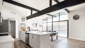 Cozinha moderna com armários brancos, uma ilha grande e vista para o exterior.