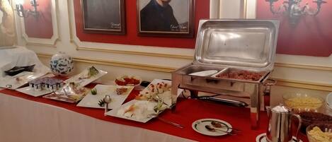 A buffet setup with various food items and a coffee pot.