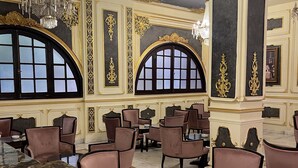 Een luxe interieur met verfijnde gouden details, grote gebogen ramen en elegante kroonluchters.