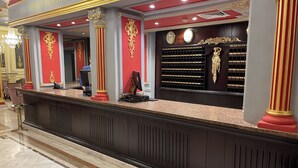 Een receptiegedeelte met een marmeren vloer, een receptiebalie en een muur met een klok en een decoratief paneel.