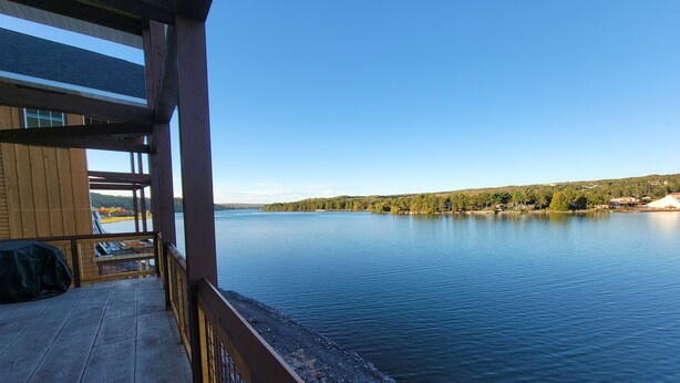 A wooden deck with a view of a calm lake and distant hills. - Waterfront Trailside Cabin 23B (Houghton)