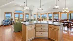 A spacious kitchen with a large island, wooden cabinets, and pendant lighting. - Happy Days: 2-Min Walk Beach, Pool, Hot Tub, 7BR (Southern Shores)