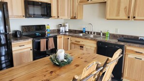 A modern kitchen with wooden cabinets, a stainless steel refrigerator, a microwave, a stove, and a dishwasher.