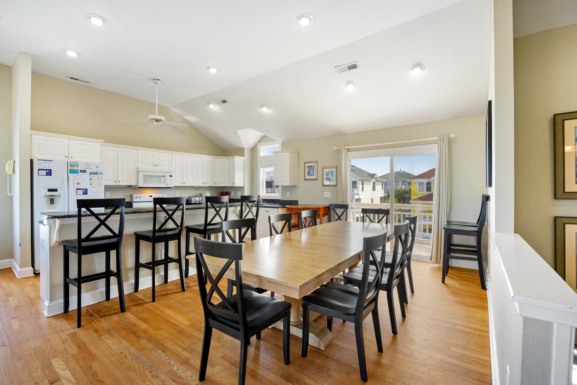 A spacious kitchen with white cabinets, a wooden dining table, and black chairs.