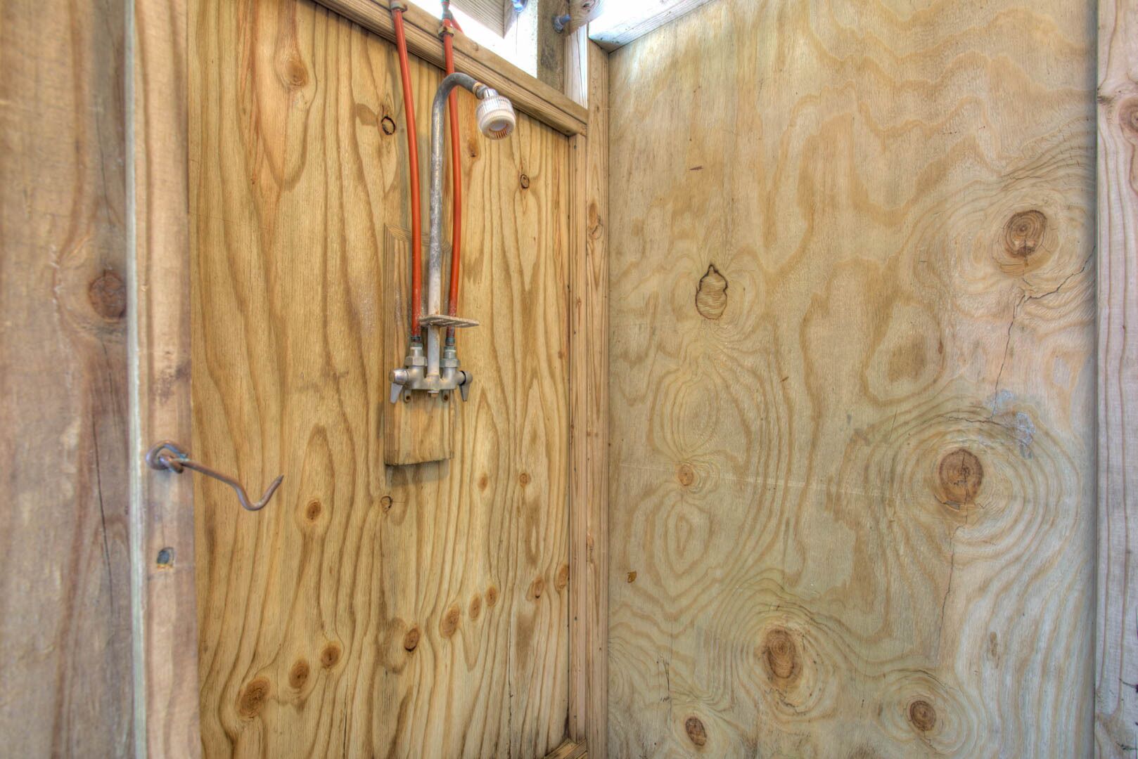 Una porta de fusta amb els accessoris de fontaneria visibles, incloent canonades i un vàlvula.