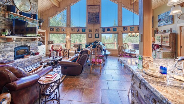Un amplio espacio habitable con chimenea de piedra, asientos de cuero y ventanas grandes que ofrecen vistas del exterior.
