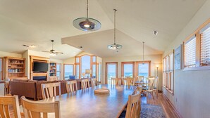 A spacious dining area with a large table and chairs, a television, and a bookshelf. - 6067 The Sand Pebble *Pool *Game Rm *Dog Friendly (Nags Head)