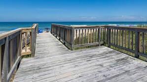 A wooden boardwalk leading to a beach with a clear view of the ocean and beach umbrellas. - 6067 The Sand Pebble *Pool *Game Rm *Dog Friendly (Nags Head)