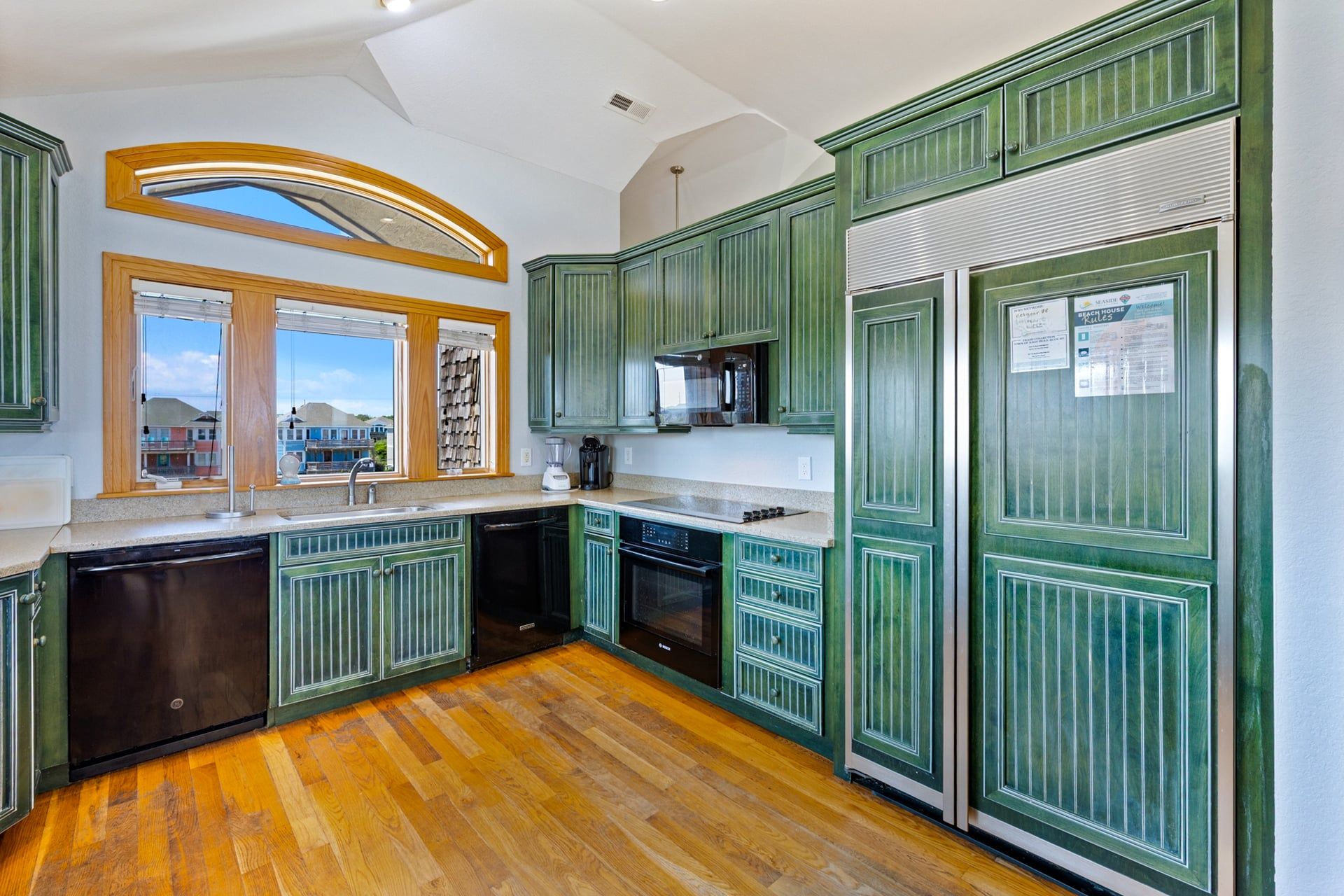 A kitchen with green cabinetry, a built-in oven, and a microwave.