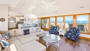 A spacious living area with a large sofa, two patterned armchairs, a glass coffee table, and a ceiling fan. - 6120 YankeeClipper*Oceanfront*Elevator*Pool*HotTub (Nags Head)
