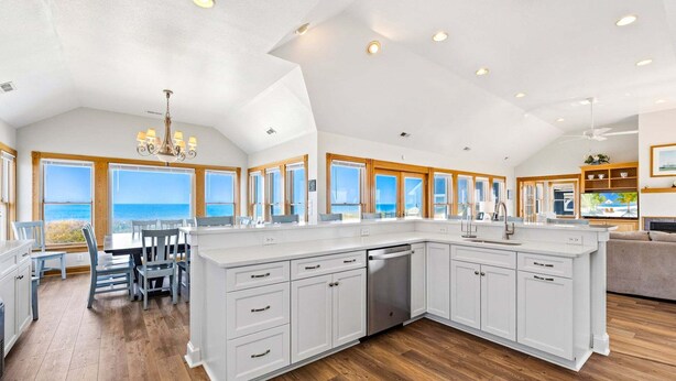 A spacious kitchen with a large island, wooden flooring, and a view of the ocean. - 6120 YankeeClipper*Oceanfront*Elevator*Pool*HotTub (Nags Head)