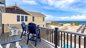 Eine Terrasse mit Sitzgelegenheiten im Freien, ein Pool und Blick auf Strand und Meer.