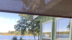Blick aus einem Fenster auf einen grünen Rasen mit See und Bäumen.