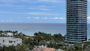 Un edificio alto con vista al océano y un yate a lo lejos.