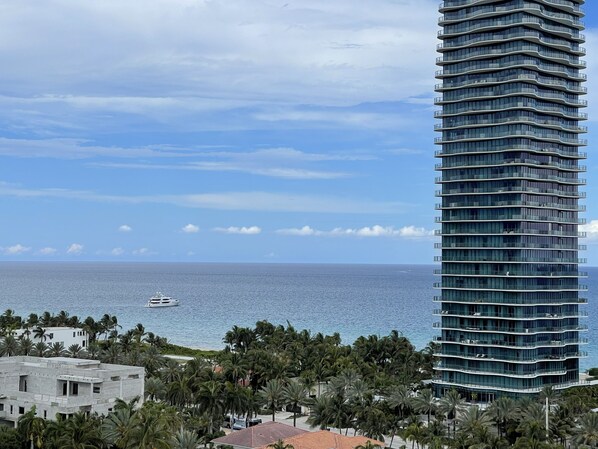 A high-rise building with a view of the ocean and a yacht in the distance.