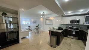 Una cocina moderna con comedor, electrodomésticos de acero inoxidable y piso de mármol.