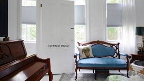 A powder room with a wooden bench, a blue upholstered chair, and a door labeled "POWDER ROOM." - Locktender Cottage · Historic cottage near Mohonk & Minnewaska, 2BR/2BA (High Falls)