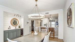 A modern kitchen with a central island, grey cabinets, and a round mirror above the sink. - Neaux Worries: Newly remodeled Ocean Front 16th Floor Pearl Condo! (Navarre Beach)