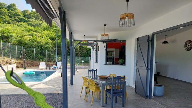 An outdoor patio with a pool, dining area, and a hammock. - Magnifique Villa Neuve Avec Piscine (Le Marin)