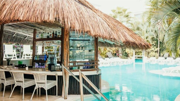 A bar area with a thatched roof, overlooking a pool with lounge chairs. - Adults only Resort in Tulum (Tulum)