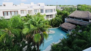 A resort with a swimming pool surrounded by lush greenery and thatched-roof structures. - Adults only Resort in Tulum (Tulum)