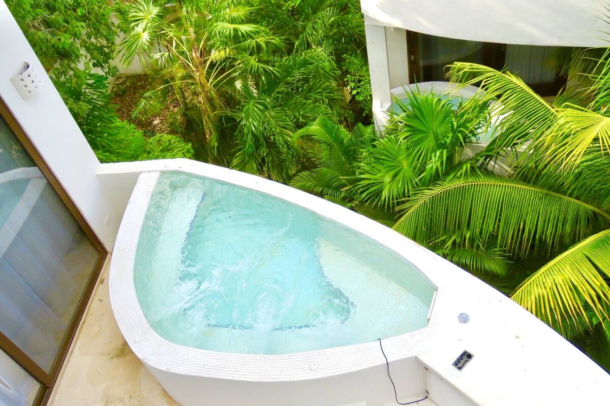 A hot tub with a tiled edge, surrounded by lush greenery.