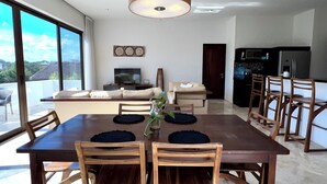 A modern dining area with a large table and chairs, a ceiling light, and a view of the outdoors. - Adults only Resort in Tulum (Tulum)