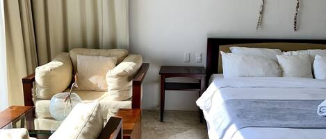A hotel room with a bed, a sofa, a small table, and a wall-mounted lamp.