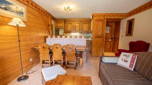 Un intérieur chaleureux, avec des murs en bois, comprenant un coin repas, une cuisine et un salon.