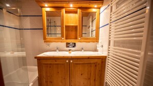 Un meuble-lavabo en bois avec deux vasques, un miroir et un espace douche.
