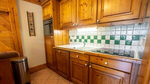 Une cuisine avec des meubles de rangement en bois, un four en acier inoxydable, un pare-feu en carrelage et un évier.