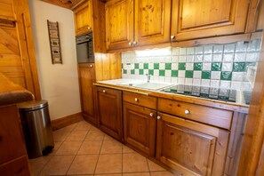 Effortlessly prepare meals in this well-equipped kitchen with a stainless steel oven, sink, and checkered tile backsplash.
