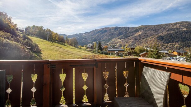 Un balcon offrant une vue sur un paysage montagneux, avec des maisons et une station-service.