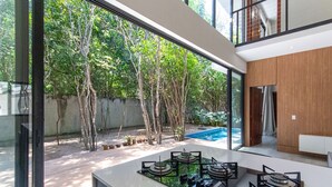 A modern kitchen with a large window overlooking a garden and a pool. - Carpediem - Casa Luxuosa em Pipa (Tibau do Sul)