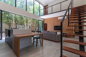 Um interior moderno com ilha de cozinha, sala de jantar e escada.