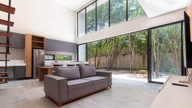 A modern kitchen with a built-in refrigerator, a dining area with a table and chairs, and a large window overlooking a garden. - Carpediem - Casa Luxuosa em Pipa (Tibau do Sul)
