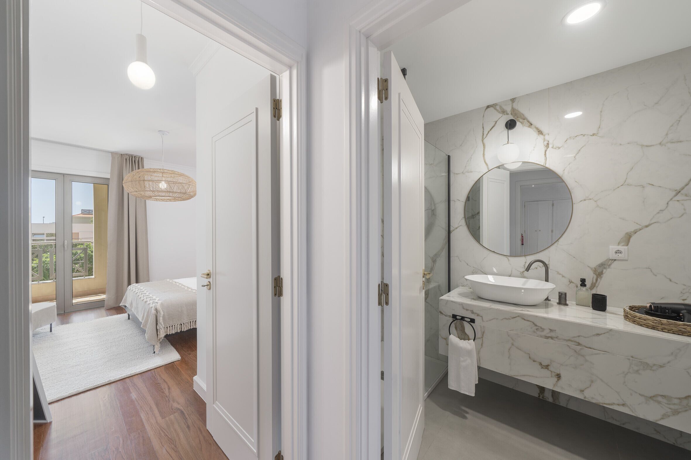 A modern bathroom with a white sink, marble walls, and a large mirror.