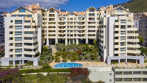A multi-story hotel with balconies, a swimming pool, and landscaped gardens.