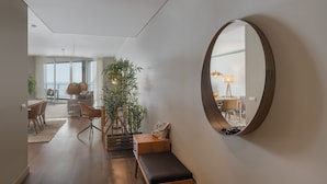 Un salon moderne avec un grand miroir, un banc et un coin repas comprenant des chaises et une table.