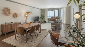 Un salon moderne avec un coin repas, de grandes fenêtres et une vue sur la mer.
