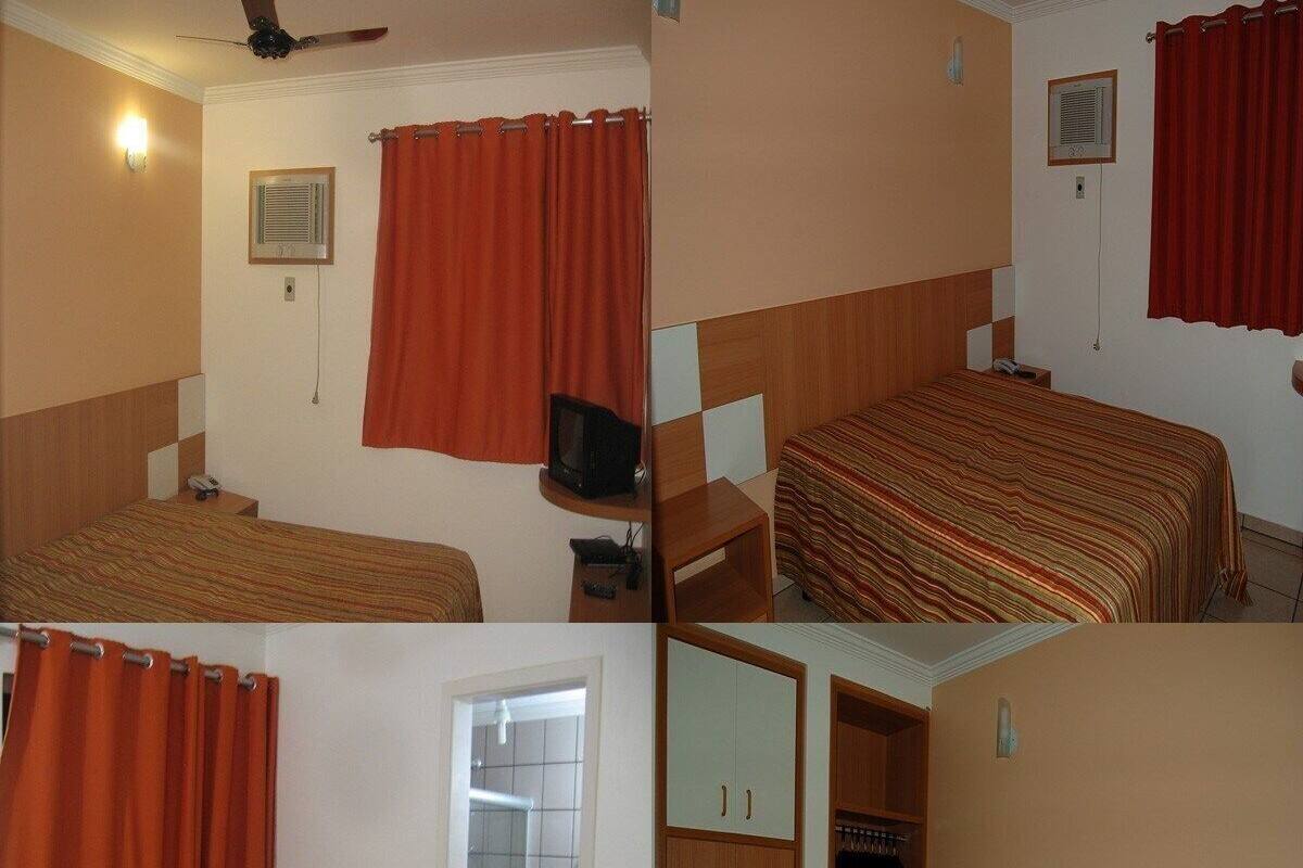 A hotel room with two beds, a TV, a wardrobe, and a bathroom with a toilet and shower.