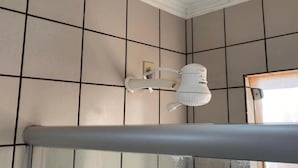 A bathroom with a white toilet, a towel rack, and a window with a view of the outside. - Aptos - DiRoma Fiori - Aluguel Economico (Caldas Novas)