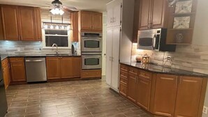 Una cocina con armarios de madera, electrodomésticos de acero inoxidable y un suelo con patrón de espiga.