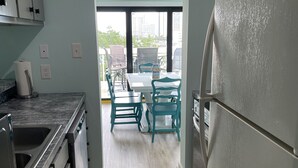 A modern kitchen with a refrigerator, sink, and cabinets. There is a dining area with a table and chairs.