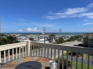 A balcony with a table, a cup, and a view of a marina with boats and a beach. - Amazing 180 degree Atlantic Ocean and beach views. (Myrtle Beach)